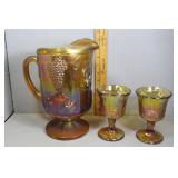 Marigold Carnival glass pitcher and two goblets wi