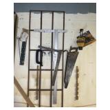 GROUP OF MISC TOOLS ON WALL, SQUARES, PRY BAR, SAW