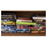 Shelf of Clive Cussler hardcover books and others