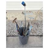 Galvanized trashcan filled with yard tools and>
