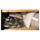 Shelf of bedding throw blankets and pillows