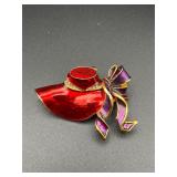 red enameled hat adorned purple ribbon brooch