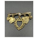 Gold tone brooch with dangling heart charms.