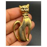 Gold tone cat brooch pin. Rhinestone eyes.