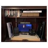 CABINET LOT TO INCLUDE VHS MOVIES, CASSETTES, 2 NEW NOTEBOOK COOLING PADS, 18" INSIGNIA TV & MORE - UP MASTER BED