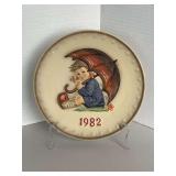 1982 M.J. HUMMEL/GOEBEL COLLECTIBLE PLATE - 12TH IN THE SERIES "GIRL WITH UMBRELLA" 7 1/2" ROUND W/ STAND