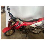 Red youth dirt bike, specifically a Honda CRF50F youth trail motorcycle, featuring a red front number plate, red plastic fenders, and a 49cc four-dirt bike. Working condition unknown