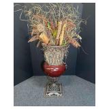 Ornamental faux floral arrangement with dried grasses and botanical elements in a dark pedestal urn or vase on an iron stand. See pictures for details.