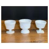 Assorted milk glass to include a small pedestal planter with embossed leaf and vine motif, pedestal sherbet/champagne cup, believed to be vintage McKee glass, and Milk Glass Harvest grape leaf sherbet