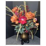 Artificial autumn floral arrangement with faux peonies, roses, and seasonal greenery placed inside a gold-finished vase on a black scrollwork metal stand. See pictures for details.