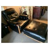 MID CENTURY MODERN BLACK VINYL W/ WOOD FRAME ROCKING SWIVEL CHAIR & OVERSIZED OTTOMAN ON WHEELS (CHAIR 36" WIDE X 42" DEEP X 35" TALL, OTTOMAN 30" SQUARE X 16" TALL (SOME DAMAGE - MISSING BUTTONS)