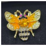 Gold-Tone Bee Brooch Featuring Yellow Enamel or Resin Wings, a Large Central Yellow Rhinestone, Red-Accented Eyes, and a Patterned Abdomen with Alternating Rows of Black and Clear Rhinestones