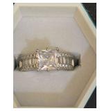 Wide-Band Princess-Cut Engagement Ring Featuring a Prominent Square-Cut Center Stone and Channel-Set Baguette Accent Stones Down the Center