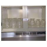 CLEAR PANELED FOOTED GLASS TUMBLERS AND JUICE GLASSES ON UPPER CABINET SHELF MARKED 1174