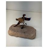 colorful metal pheasant figurine mounted on a rock