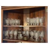 2 shelves of clear glassware, 3 red coasters, vase
