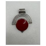 A sterling silver pendant with a striking red