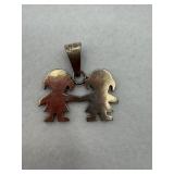 A sterling silver pendant of two children holding