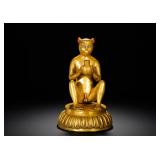 A GILDED BRONZE STATUE OF A MONKEY OFFERING...