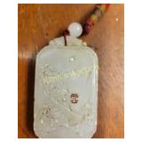 carved white jade pendant attached to a red cord