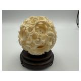 ANTIQUE CARVED BONE PUZZLE BALL ON A WOOD
