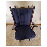 Wood rocking chair with turned spindle frame, dark finish and blue patterned upholstered seat and back cushions.