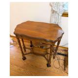 Vintage wood side table with shaped top, turned legs, stretcher base and lower shelf, approximately 29" tall x 32" wide x 20" deep.
