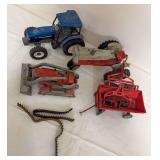 Group of vintage and later farm toys including New Holland TM150 tractor, Fordson tractor, loader and red farm implement, along with loose rubber tracks as shown. Mixed makers, ages and condition.