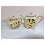 Hall Autumn Leaf pair including one square-bodied lidded teapot and one rounded lidded teapot, both with gold trim. Square teapot features a recessed rectangular lid (see roughness); rounded teapot ha