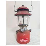 Coleman Model 200A pressure lantern with red fount and red porcelain ventilator, clear Pyrex Coleman globe and wire bail handle; marked 7/72. Shows surface wear, dust and age-related use.