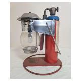 Clayton & Lambert Mfg. Co. propane lantern with red base and upright fuel-cylinder housing, silver-tone lantern assembly, clear globe and blue-topped propane cylinder as shown. Shows paint wear, oxida