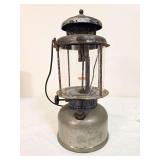 Coleman Quick-Lite pressure lantern marked 8/26, with silver-tone fount and ventilator, clear Coleman globe and wire bail handle. Shows age-related oxidation and finish wear.