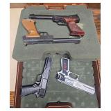 Four Crosman BB/pellet pistols in foam-lined hard case, including a long-barrel Crosman target-style pistol with marbled grip, a Crosman American Classic long-barrel pneumatic pistol with wood-tone gr