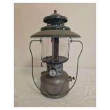 Coleman Model 228D pressure lantern with silver-tone fount, green porcelain ventilator, clear Coleman/Pyrex globe and wire bail frame; marked A/49. Shows oxidation and general age-related wear.