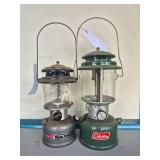 Coleman Dual Fuel & Vintage Green Pressure Lanterns. Includes gray Dual Fuel lantern and earlier green double-mantle pressure lantern with clear globes and wire bail handles; shows age-related wear, o
