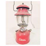 Coleman Model 200A pressure lantern marked 7/62, with red painted fount, matching red porcelain ventilator, clear Coleman globe and wire bail handle. Shows paint loss and age-related wear.