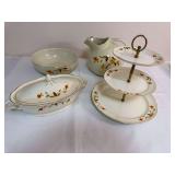 Four-piece Hall Autumn Leaf serving group including a covered casserole, large pitcher, serving bowl and three-tier serving stand, all with gold trim. Pieces carry Hall’s Superior Quality Kitchenwar