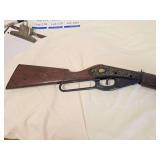 Vintage Daisy Model 111 lever-action BB gun with brown wood-tone stock and forearm, black receiver and decorative puma/cougar graphic with gold scrollwork. Shows general age-related wear.