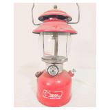 Coleman Model 200A pressure lantern marked 9/75, with red painted fount, matching red porcelain ventilator, clear Coleman globe and wire bail handle. Shows paint wear, soiling and age-related use.