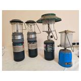 Four portable propane lanterns in assorted styles and finishes with glass globes, ventilators and carrying handles as shown; mixed makers and condition.
