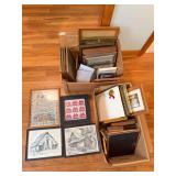 Two boxes containing assorted vintage picture frames, framed prints, needlework and other framed decorative pieces in a variety of sizes and styles.