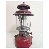AGM Model 2572 pressure lantern with red fount, dark maroon ventilator, clear globe, wire bail frame and AGM identification plate. Shows paint wear, oxidation, dust and general age-related use.