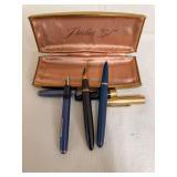 Three vintage fountain pens in blue and black finishes, with assorted caps and Parker “51” presentation case as shown. Middle pen has a 14K gold nib.