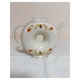 Hall Autumn Leaf lidded Donut-form teapot with circular center opening, gold trim and pedestal base. Distinctive round body with integrated handle and short angular spout; lid has a rectangular tab-st