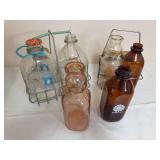 Group of vintage milk bottles with wire carriers, including clear and amber glass examples and assorted dairy markings as shown. Mixed sizes, makers and condition.
