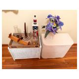 White wicker hamper and wicker storage piece with assorted household decor including glass lamp chimneys, candleholder, artificial floral arrangement and additional decorative items as shown.