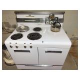 Vintage white Frigidaire electric range with four coil burners, chrome trim and period clock/timer control panel. Untested and located in the basement; buyer is responsible for removal.