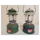 Pair of Coleman LP Gas Propane Lanterns. Two Coleman propane lanterns with green painted components, clear globes and wire bail handles; shows general age-related use, finish wear and oxidation.