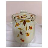 Two vintage Hall Jewel Tea Autumn Leaf pieces comprising a Hall’s Superior Quality Kitchenware rayed cookie jar with fitted lid and a matching lidded rayed coffee pot, both in cream glaze with Autum