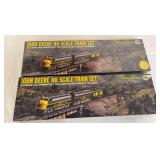 Two Athearn John Deere HO scale train sets featuring 75th Anniversary Model D tractors and John Deere Railway System equipment. One set is new in box and the other has been opened.